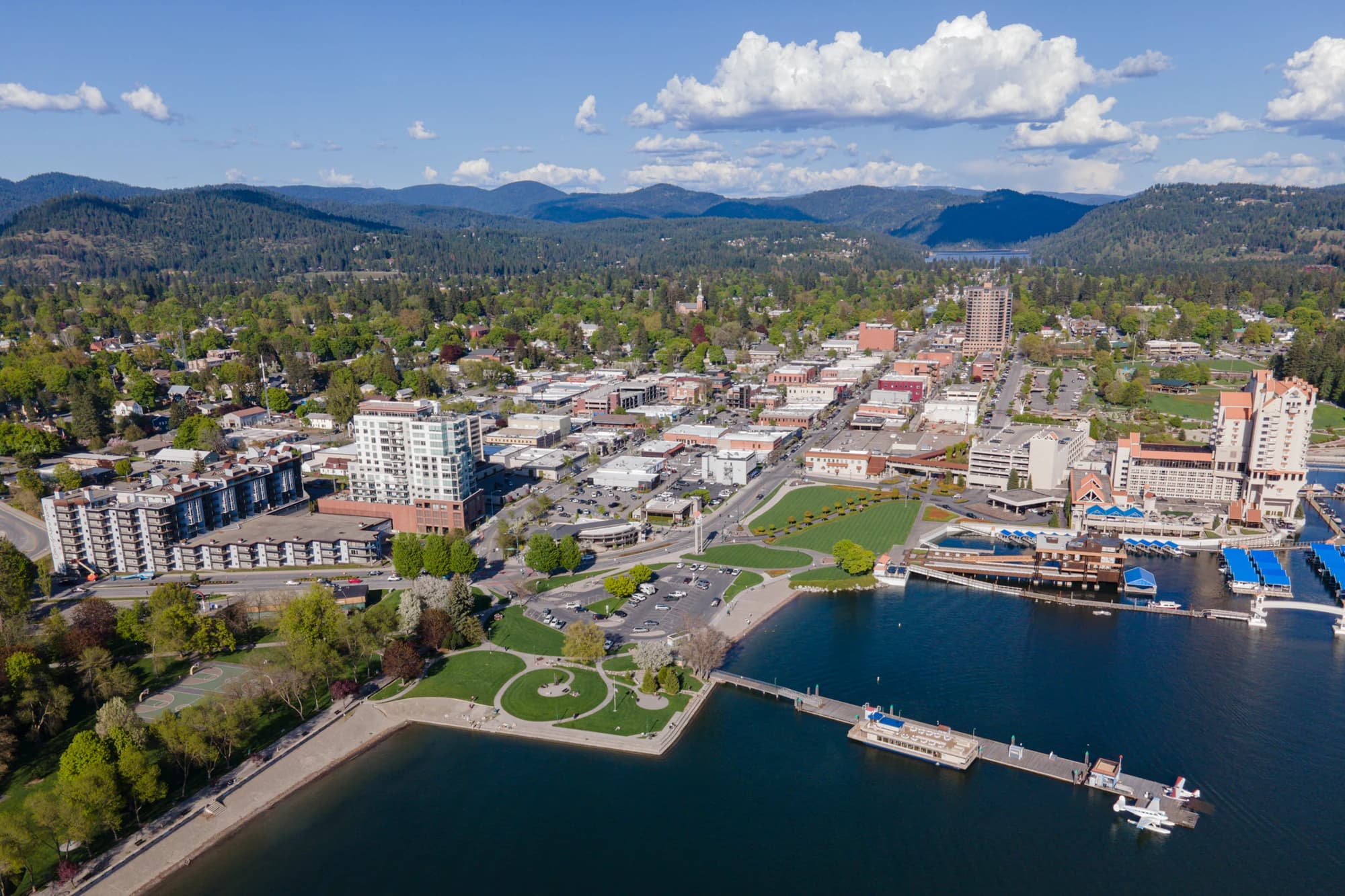 Aerial view of downtown Coeur d'Alene, Idaho, with its lakefront resort, marina, and surrounding forested mountains