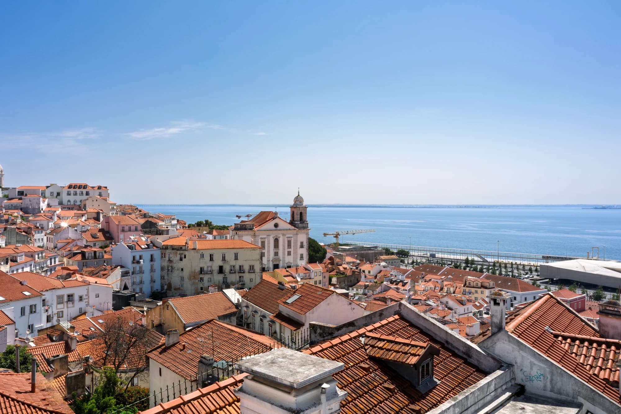 Terracotta rooftops of Lisbon's Alfama district overlooking the Tagus River