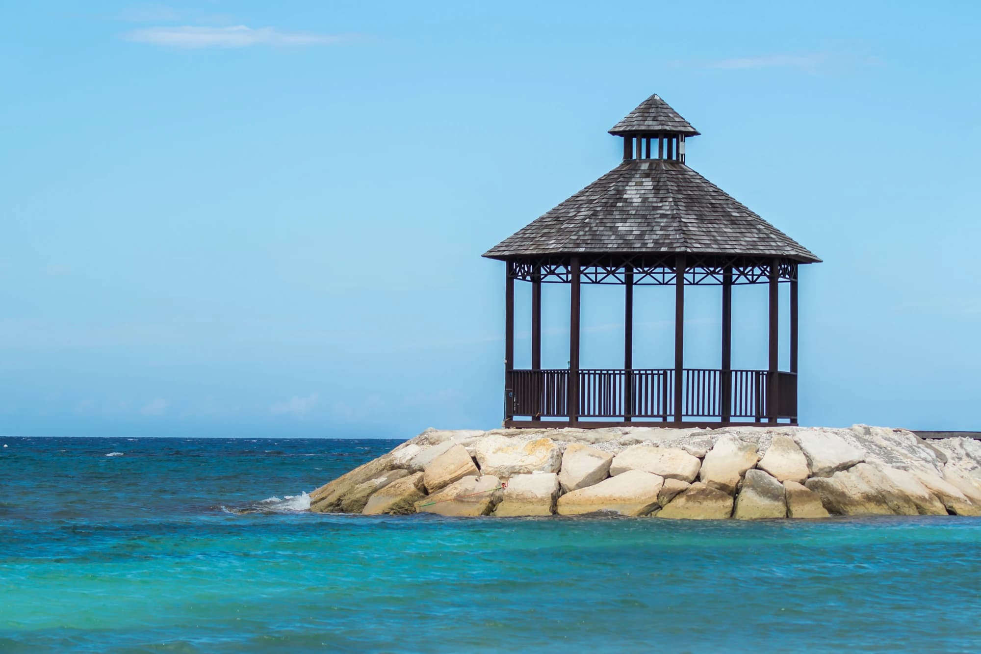 Wooden gazebo on a rocky point overlooking turquoise water in Montego Bay, Jamaica