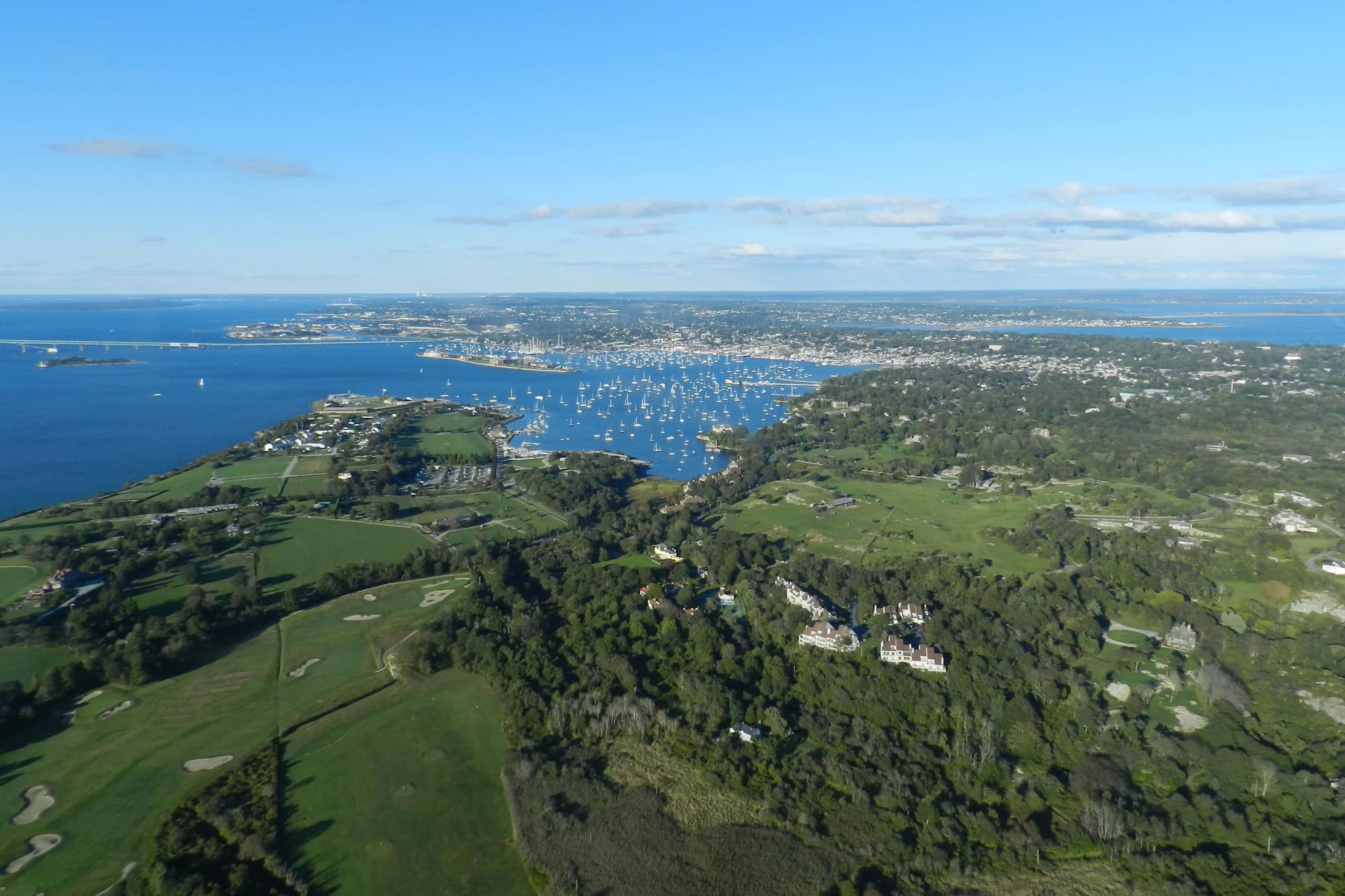 Aerial view of Newport Harbor, Rhode Island, filled with sailboats, with the town and Newport Bridge in the distance
