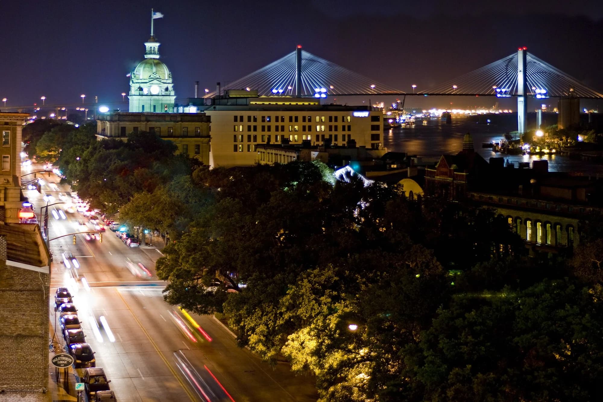 Evening rooftop view of downtown Savannah, Georgia, looking northwest toward the illuminated City Hall dome and the Talmadge Memorial Bridge over the Savannah River