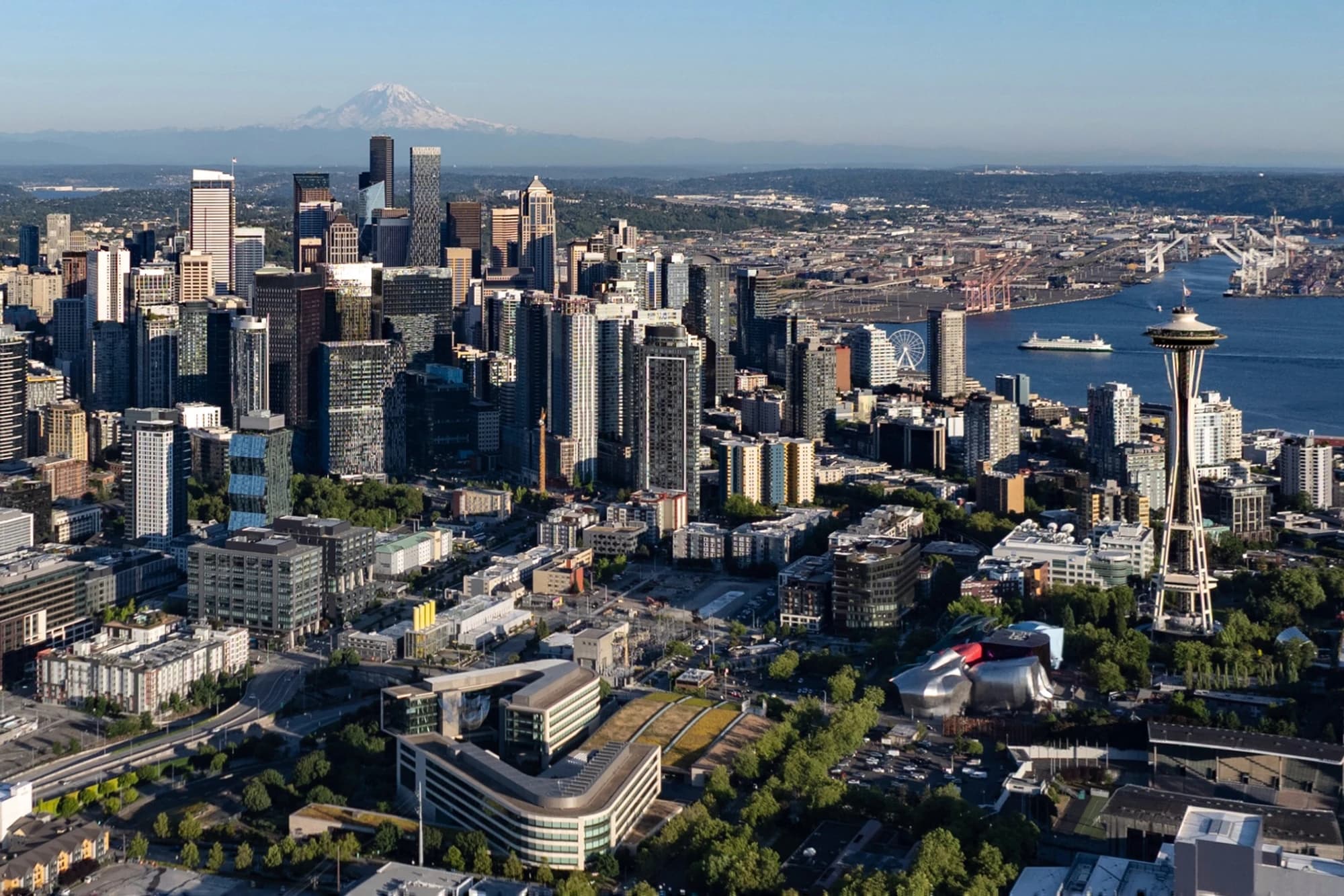 Aerial view of downtown Seattle's skyline with the Space Needle, Elliott Bay, and Mount Rainier in the background