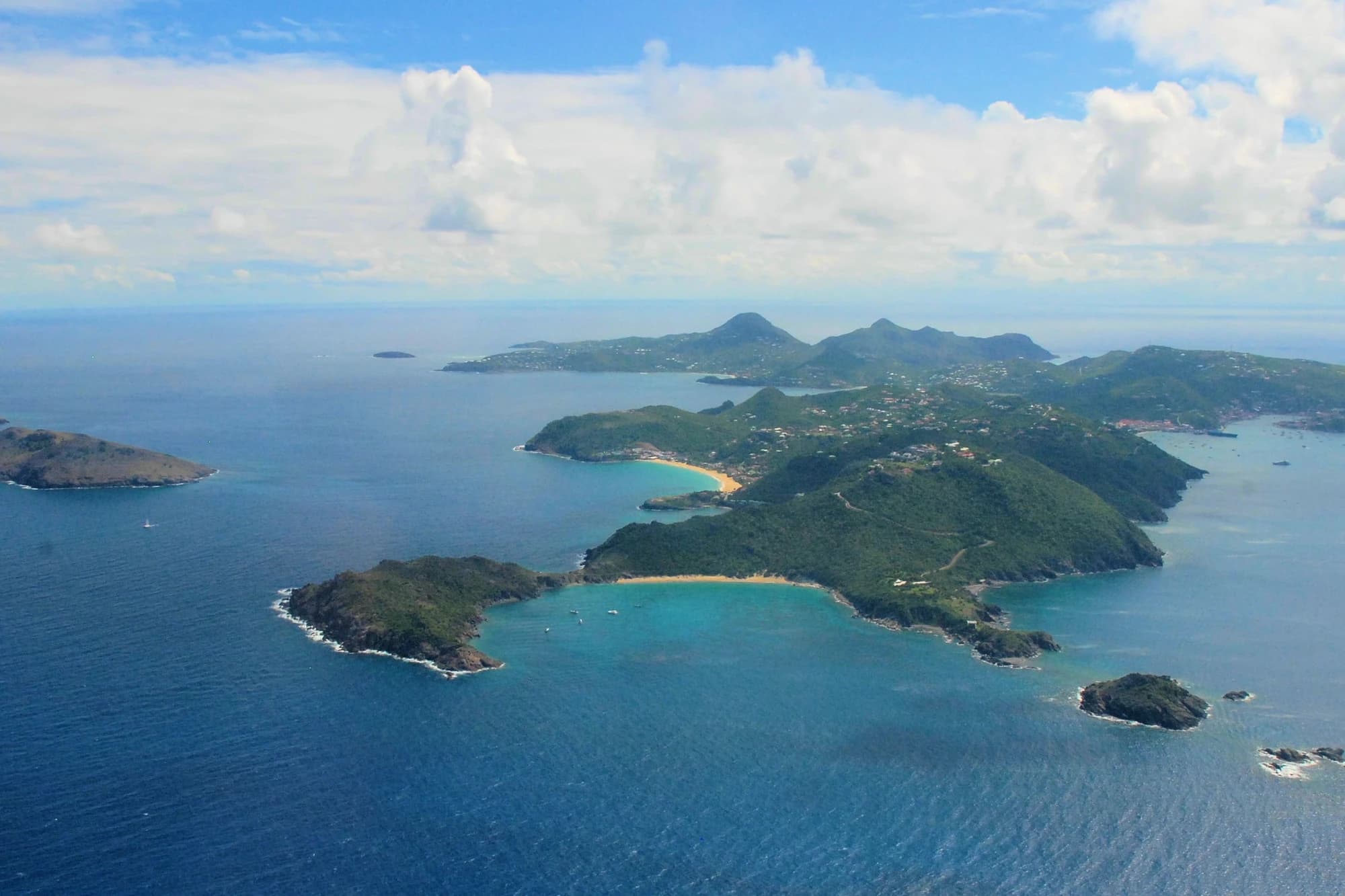 Aerial view of the hilly, island coastline of Saint Barthélemy with turquoise coves and surrounding sea