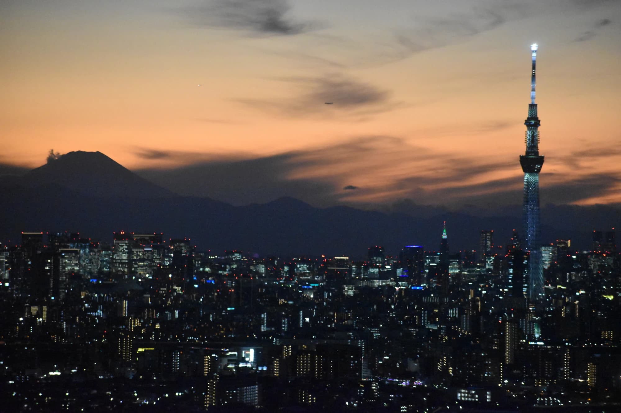Tokyo's skyline at sunset with Mount Fuji and Tokyo Skytree visible in the distance