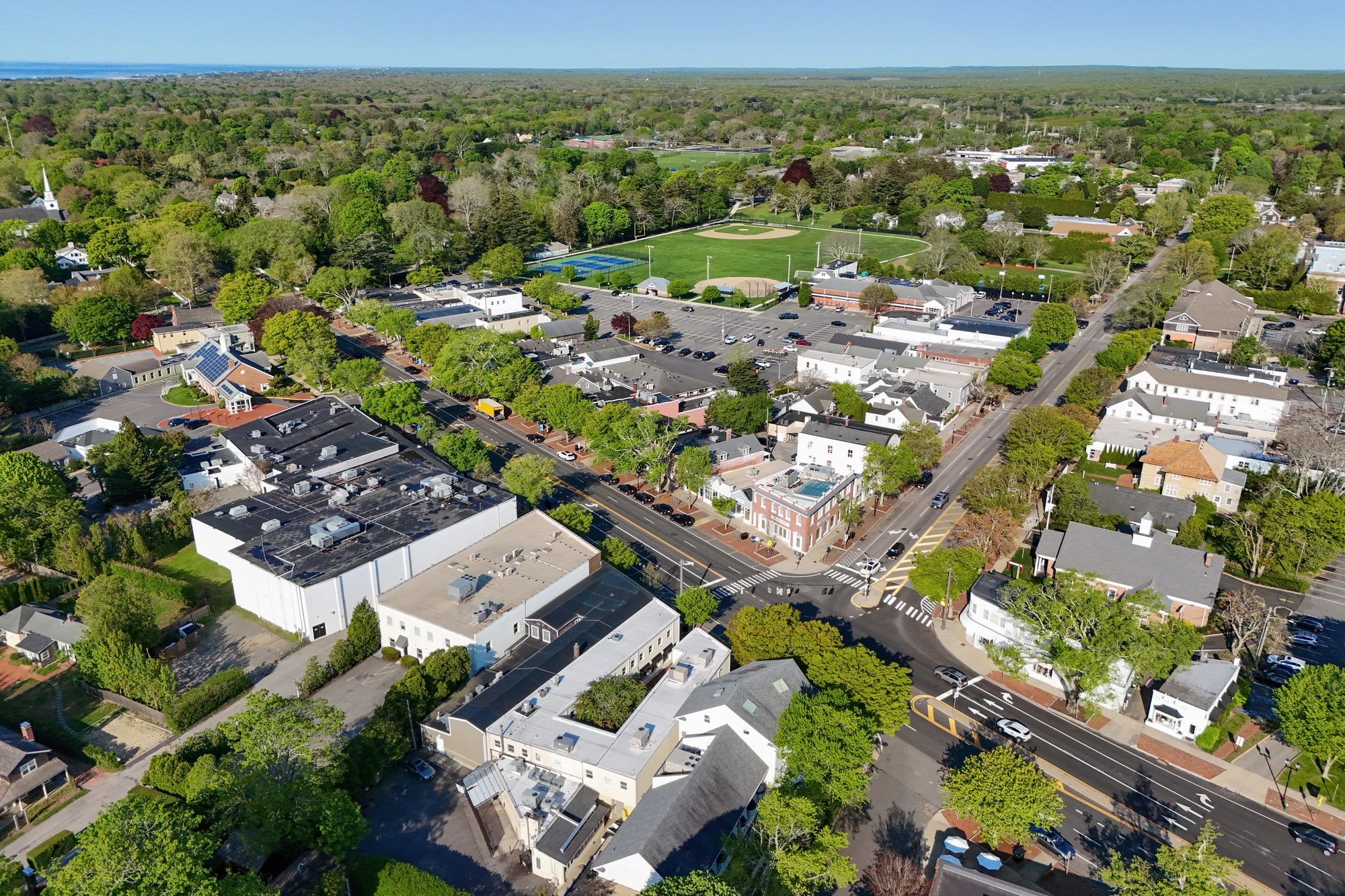 Aerial drone view of the village center of East Hampton, New York, showing tree-lined Main Street and historic buildings