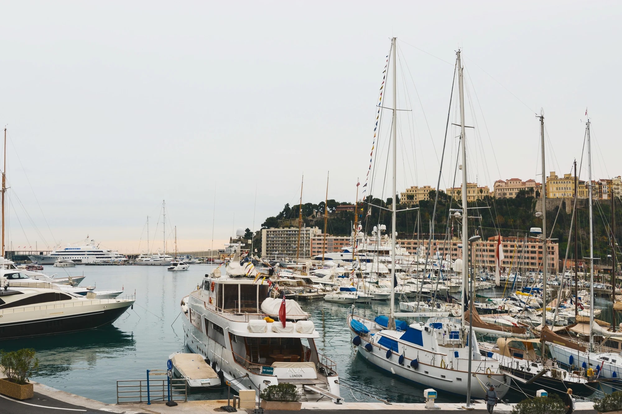 Superyachts and sailboats moored in Port Hercule, Monaco, with the Prince's Palace on the hill above