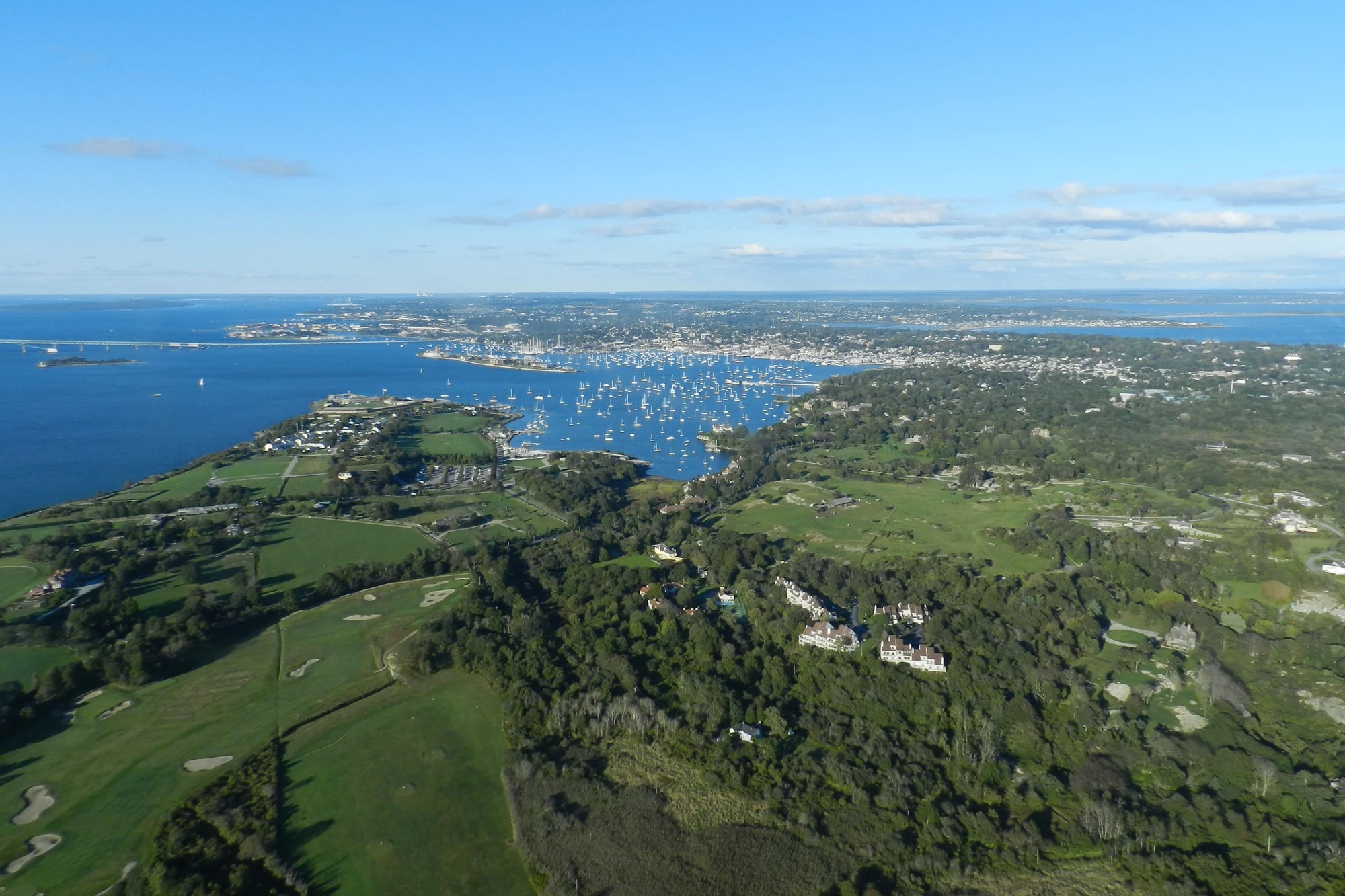 Aerial view of Newport Harbor, Rhode Island, filled with sailboats, with the town and Newport Bridge in the distance